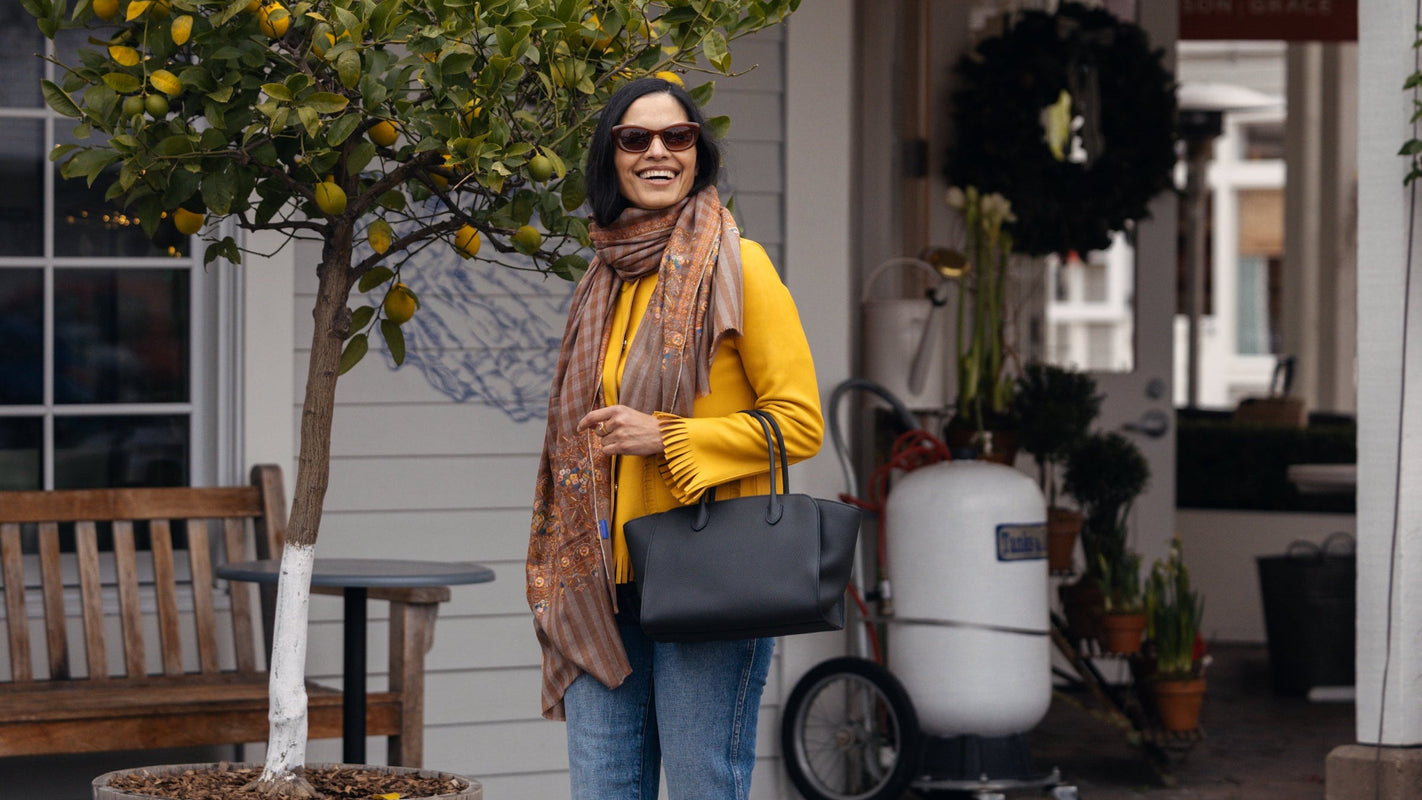 Woman in yellow top and blue jeans walking past a store with decorative elements.